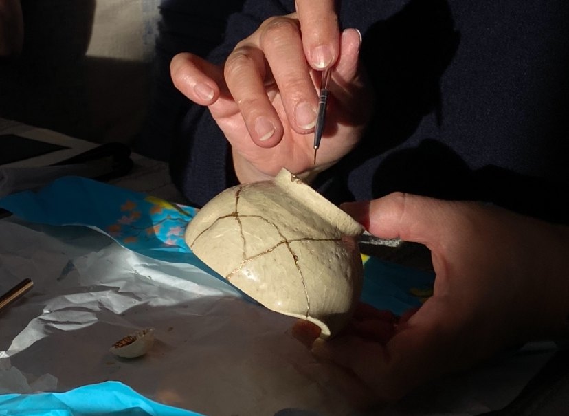 Hands carefully tracing a repaired seam on a small ceramic cup